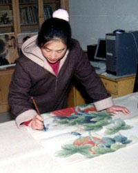 Qin Xia works on another one of her paintings